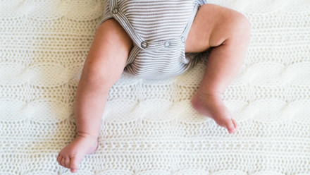 一个长着胖乎乎小腿的婴儿躺在床上