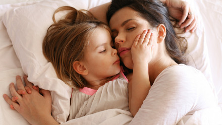 一位母亲试图入睡，她的小女儿抓着她的脸