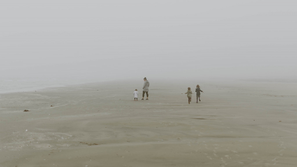 三个孩子和妈妈在海滩上玩