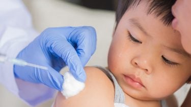一个孩子在母亲的安抚下注射了流感疫苗。