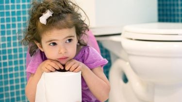 小女孩坐在马桶上拿着手纸