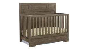 韦斯特伍德设计铸造可转换婴儿床，一个棕色木制婴儿床，上面有斑点床单