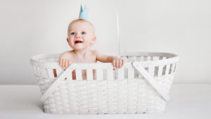 婴儿戴着纸王冠，坐在白色的篮子里