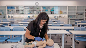 一名接受助产士培训的妇女在模拟体检中检查婴儿娃娃的心跳