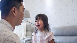 近距离的亚洲父亲安慰治疗哭泣的女儿在客厅的房子。