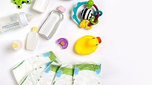 各种婴儿用品摆放在白色的表面上，包括尿布、婴儿油和一只黄色的橡胶鸭子