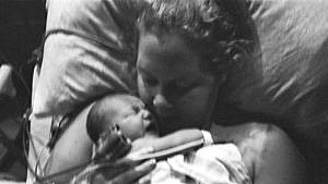 艾米·舒默产后在病床上低头凝视着婴儿吉恩