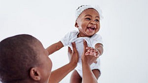 父母抱着一个笑着的婴儿的照片