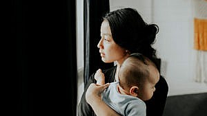 一位母亲抱着孩子看着窗外