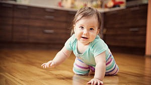 一个婴儿在厨房里笑着爬着