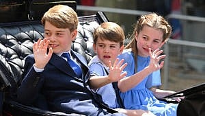 在阅兵式庆祝活动中，乔治王子、路易斯王子和夏洛特公主坐在一辆马车上，向人群挥手致意