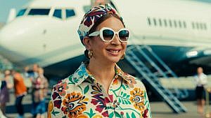 《战利品》中的玛雅·鲁道夫戴着太阳镜，搭配印花发带和衬衫