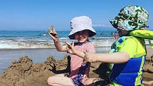 两个孩子在沙滩上玩沙。