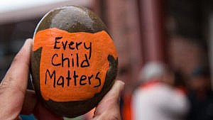 一块岩石的特写镜头，上面画着一件橙色t恤，上面写着“每个孩子都很重要”。