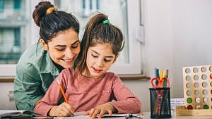 一张母亲和女儿一起做作业的照片。