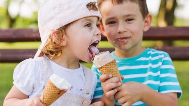 可爱的小男孩和他的妹妹分享冰淇淋