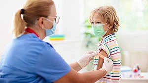 一名护士在接受疫苗注射后将创可贴贴在一个小男孩的手臂上