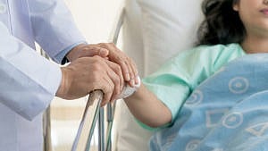 医生握着一个躺在病床上的女人的手